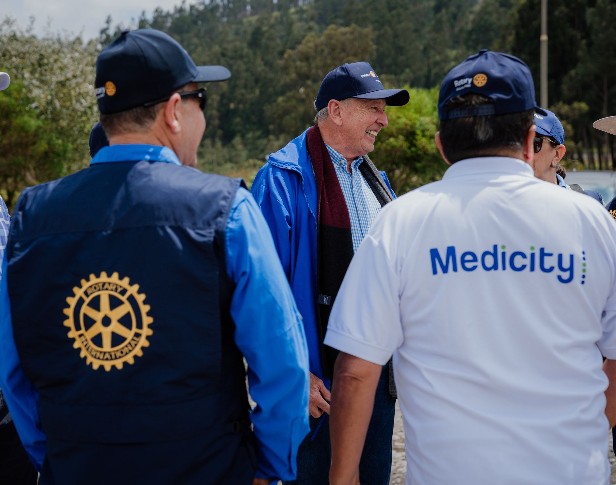 Voluntarios con chalecos y gorras de Rotary International conversan con personal de otra organización aliada durante la jornada de la Minga Mundial por el Ambiente