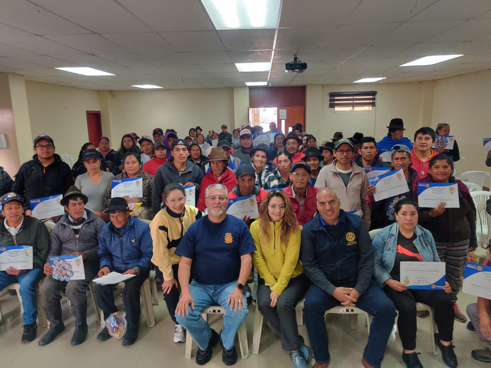 Participantes de la comunidad de Pasa sostienen sus certificados junto a socios del club al terminar el taller